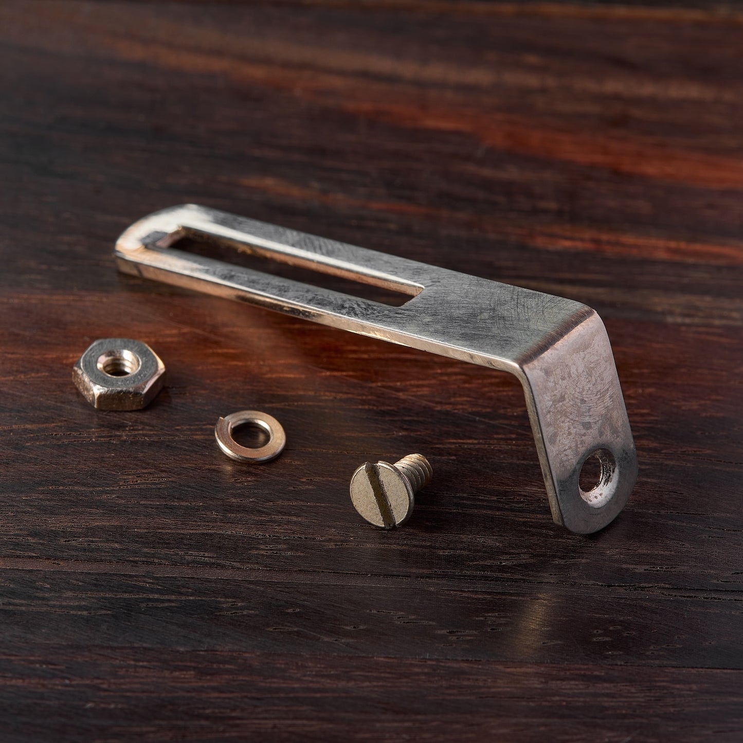 Pickguard bracket with screws on a wooden surface