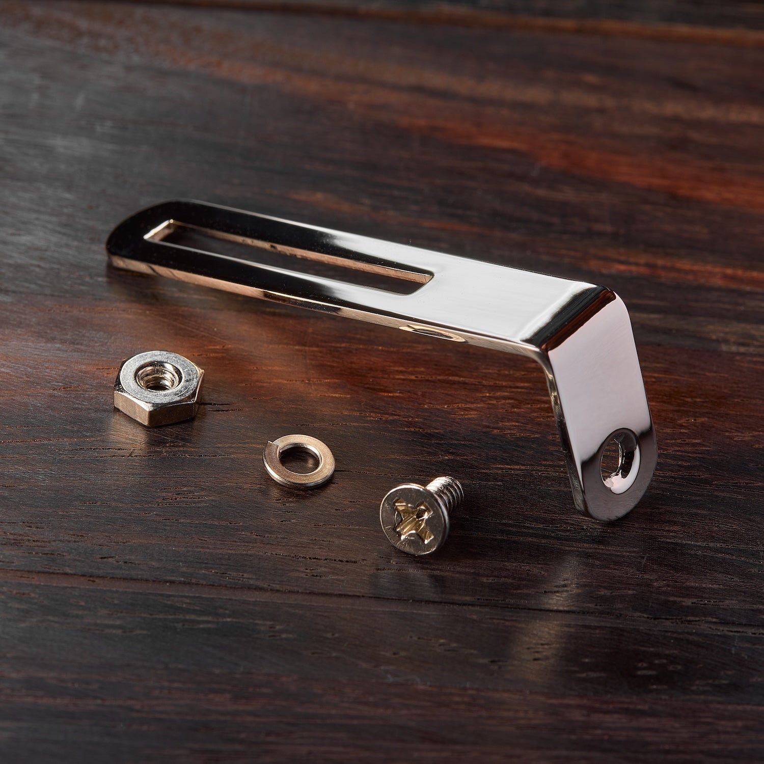 Pickguard bracket with screws on a wooden surface