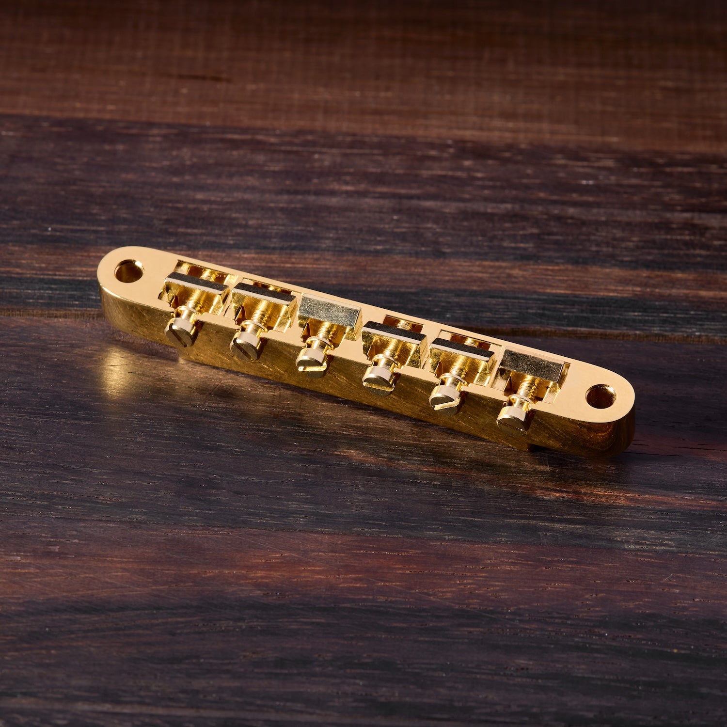 Gold guitar bridge on a wooden surface