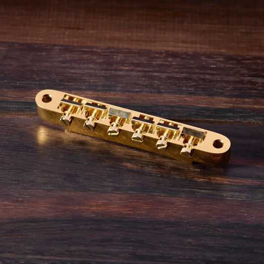 Gold guitar bridge on a wooden surface