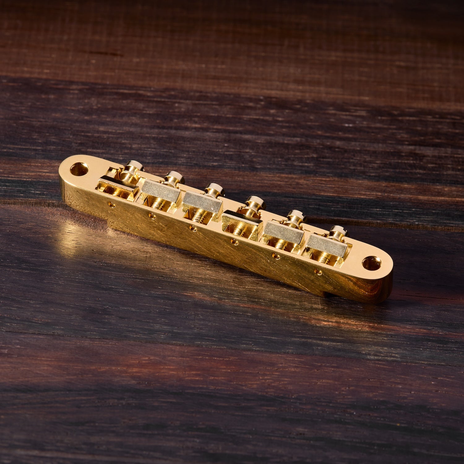 Gold guitar bridge on a wooden surface