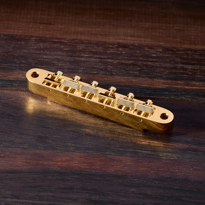 Gold guitar bridge on a wooden surface
