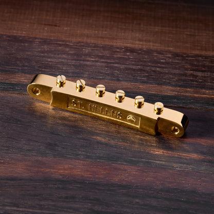 Gold guitar bridge on a wooden surface