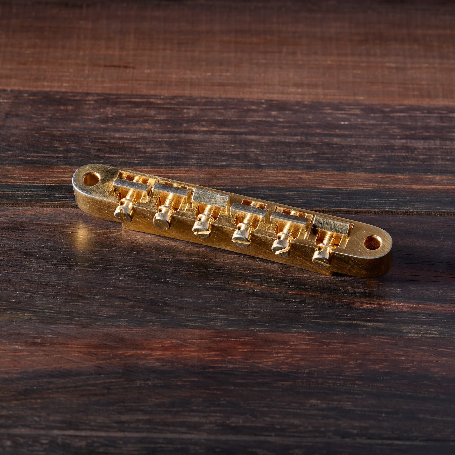 Gold Aged guitar bridge on a wooden surface