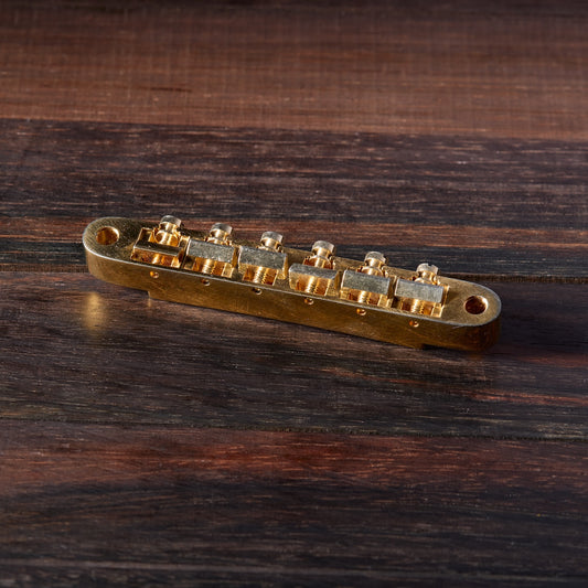 Gold Aged guitar bridge on a wooden surface
